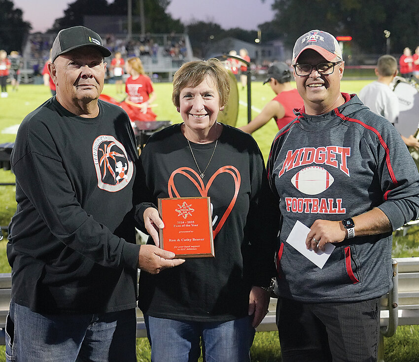 ELC Booster Club member Greg Deim, right, presents Ron and Cathy Beaver with the 2024-25 Estherville Lincoln Central Fans of the Year award during Friday’s football game against OABCIG.