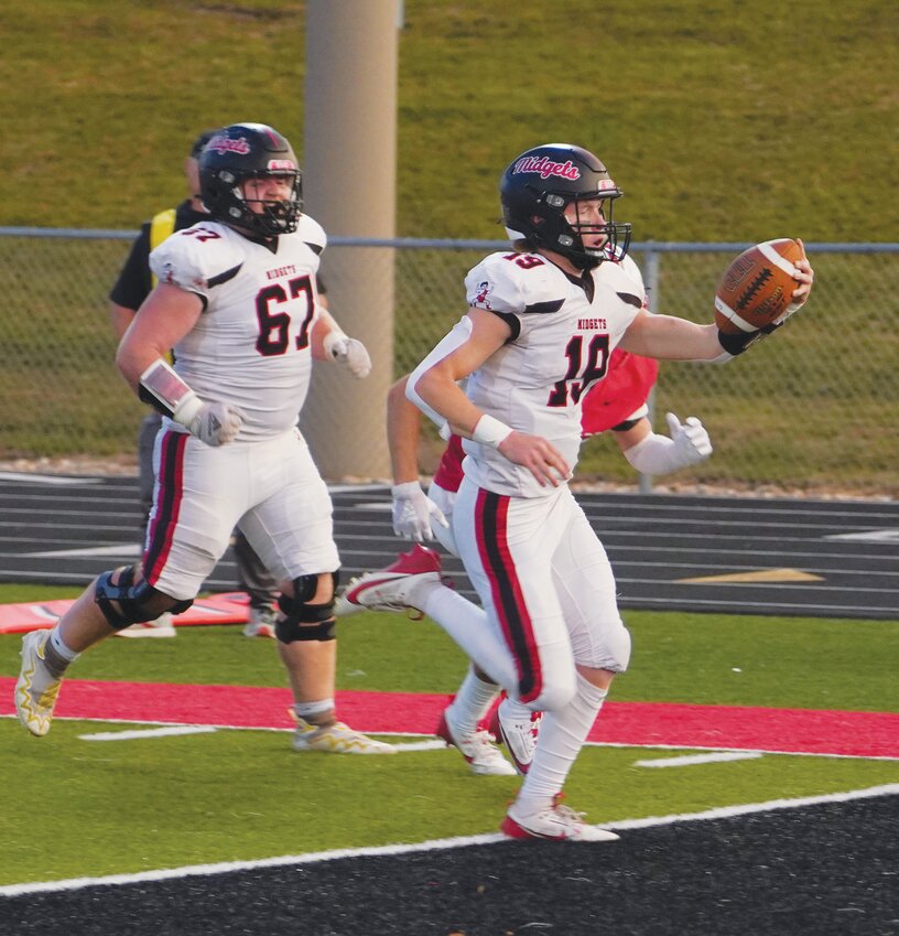 Quarterback Layton Yager (19) scores Estherville Lincoln Central’s first rushing touchdown of the season on this 10-yard run against Algona on Friday.  Behind Yager is lineman Liam Brown (67).