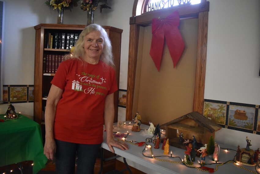 Trudie Roloff poses with a nativity scene featuring a wooden stable built by her husband. The set is one of her favorites.