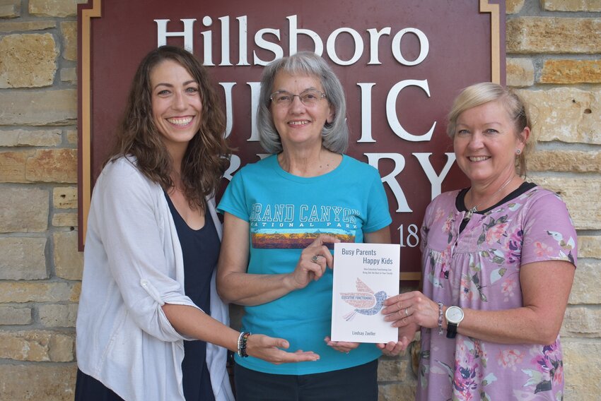 Author Lindsey Zoeller (left) poses with Hillsboro Woman’s Civic Club member Carol Wolfenden (center) and Hillsboro Public Library director Jackie Pysarenko (right) as she and the Hillsboro Woman’s Civic Club donates a copy of her book, Busy Parents Happy Kids, to the library in memory of Barb Santas. The book is focused on ways to help improve executive functions in children and adults.