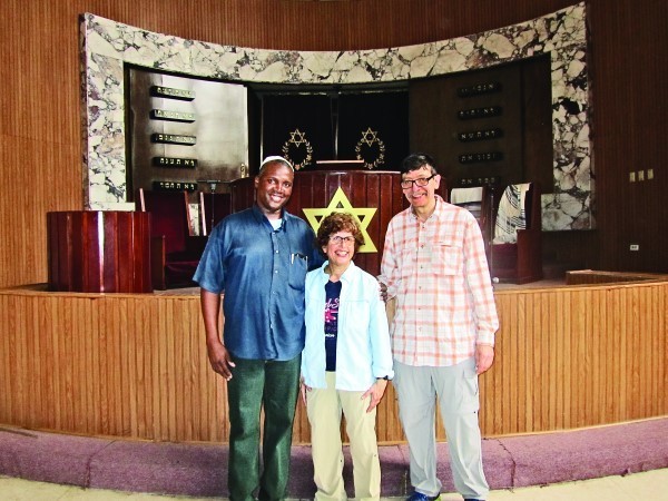Lynne Glickman, Mark Kanter with their guide in front of the  bimah at Temple Beth Shalom in Havana.