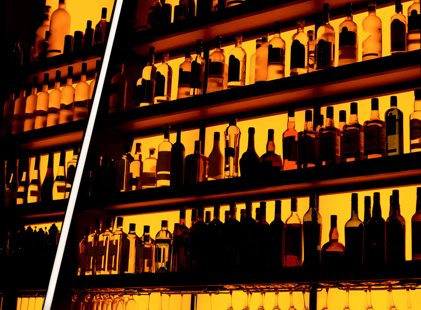 Rows of bottles sitting on shelf in a bar.