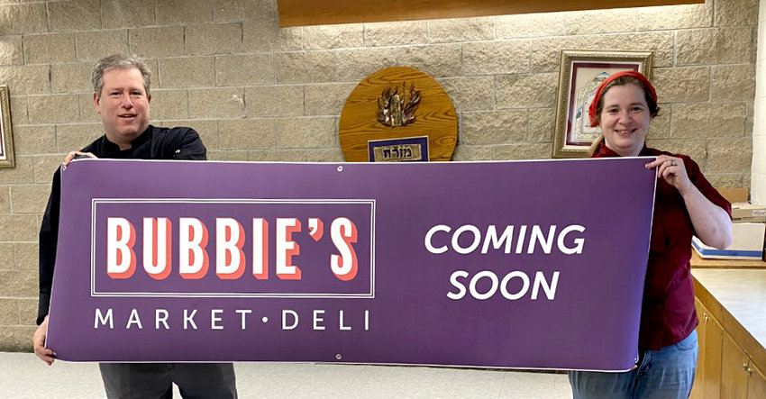 Jeffrey Ingber and Freda Ronkin hold the sign that will be displayed in the window of the new market and deli they plan to open soon.