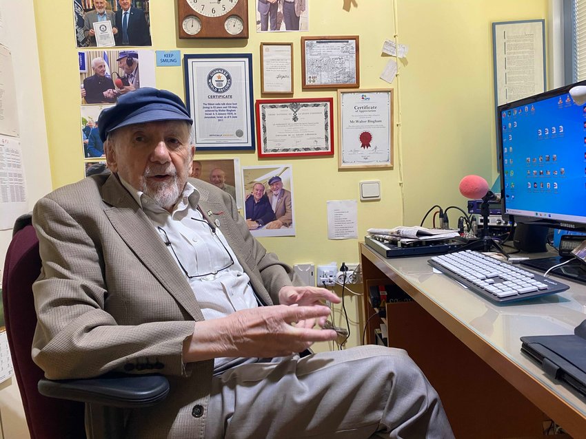 Longtime radio journalist Walter Bingham sits in his office behind a wall filled with memorabilia, including a telegram regarding an award he won from the United Kingdom's King George VI.