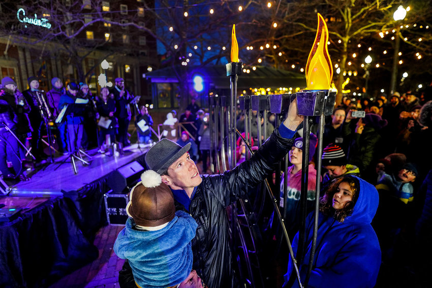 Brendan Rose, of Providence, lights the menorah with his son Lev, 1, on Dec. 18 at the Hanukkah Spectaculah in Biltmore Park in downtown Providence.