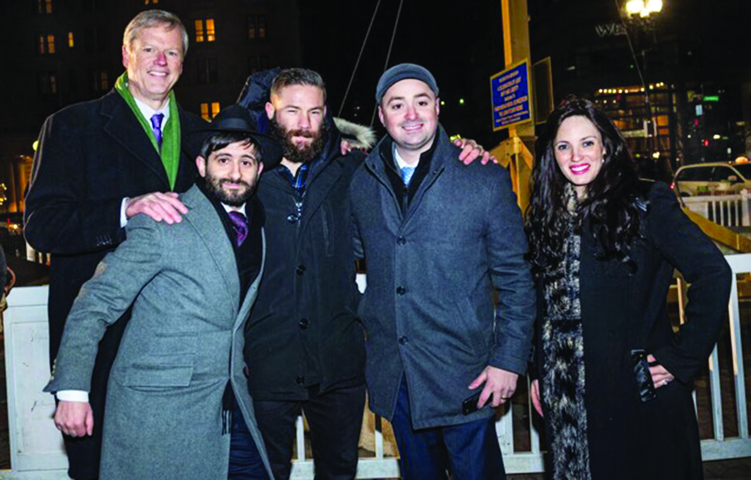 In Massachusetts, New England Patriots player Julian Edelman, above, lights the menorah in Copley Square (in the lift with him are Governor Charlie Baker and Emily Becker whose family are Chabad supporters).
And later, left, at the event that took place Dec. 6, Edelman is pictured with, (left to right)  Governor Charlie Baker, Rabbi Mayer  Zarchi of Chabad Boston,  Boston Councilman Josh Zakim, and Rebbetzin Chenchie Zarchi.