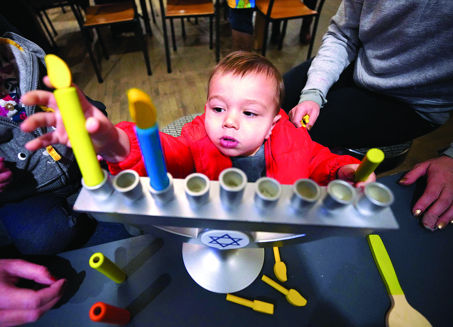 PROVIDENCE, RI--Friday, December 20, 2019--Story time at Knead Donuts on Elmgrove Ave.  PICTURED IS: Nathan Gutman, 15-months-old, playing with a menorah, after story time.  Photo Glenn Osmundson/Jewish Rhode Island