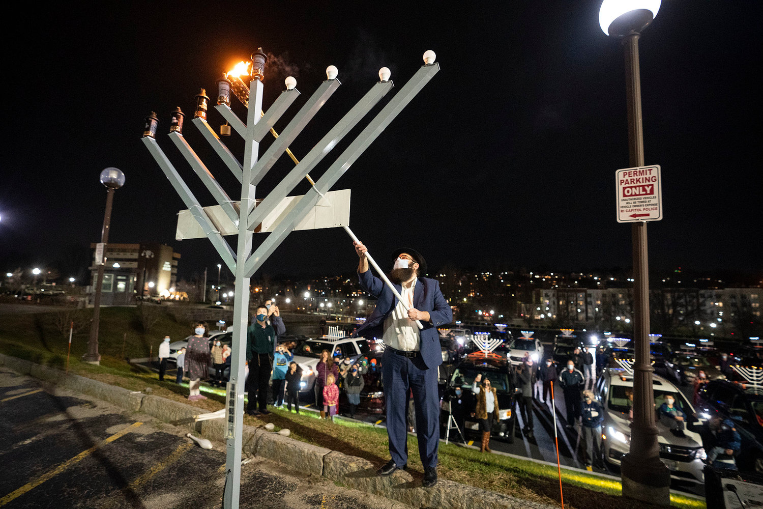 After a menorah car parade through Rhode Island on Dec. 13, 2020, Rabbi Aryeh Laufer lights the menorah set up outside the Rhode Island State House.