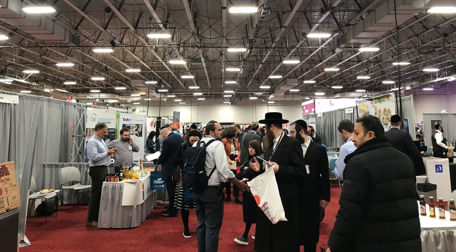 Attendees at Kosherfest, a food industry trade show held in Secaucus, New Jersey, arrive with empty tote bags on each shoulder, ready to fill up with product samples and vendors' business cards, Nov. 9, 2021. (Julia Gergely)