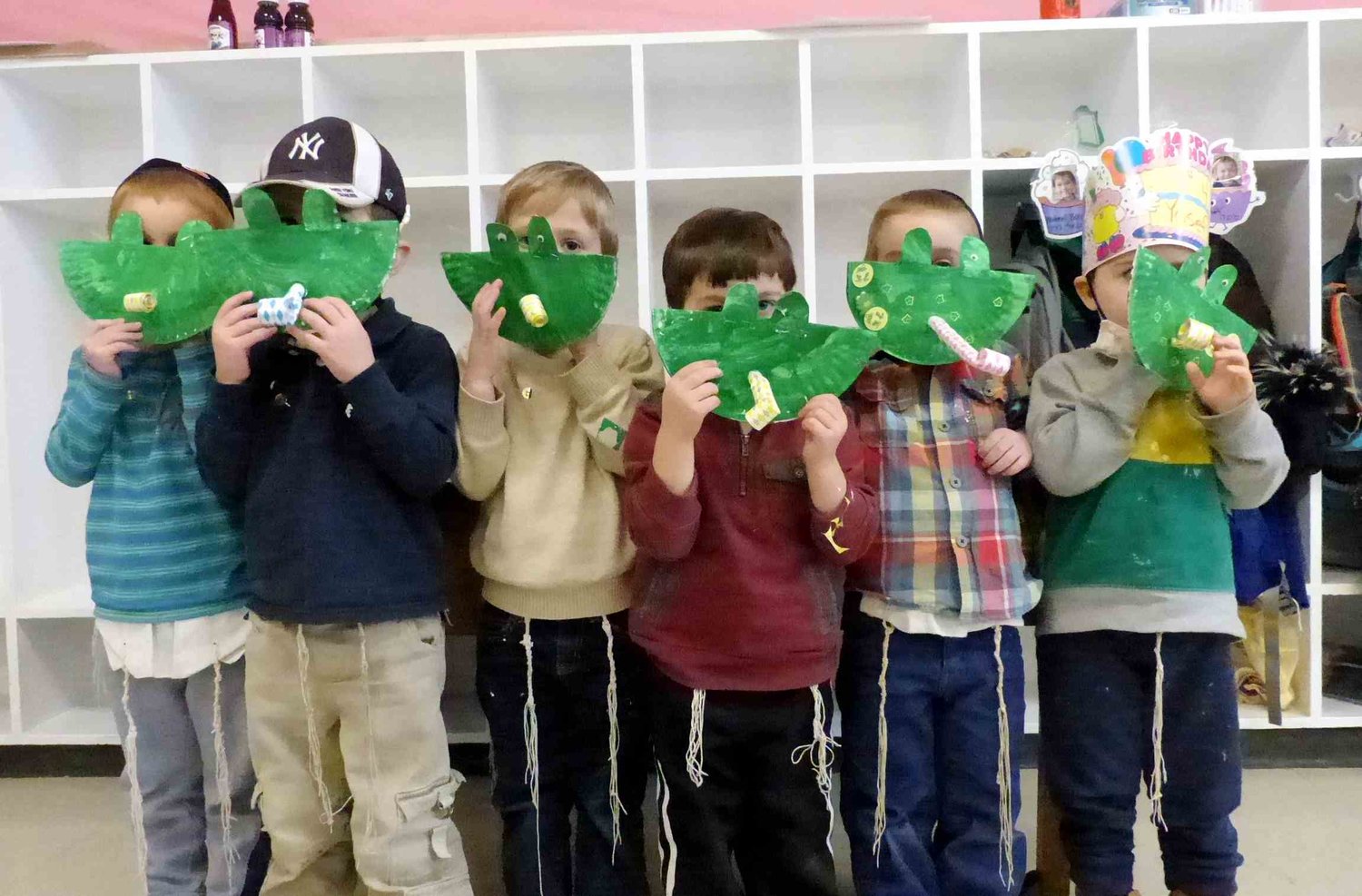 Pre-K students at Providence Hebrew Day School hide behind the frog masks they made when learning about the Plague of Frogs in Parsha Vaera.