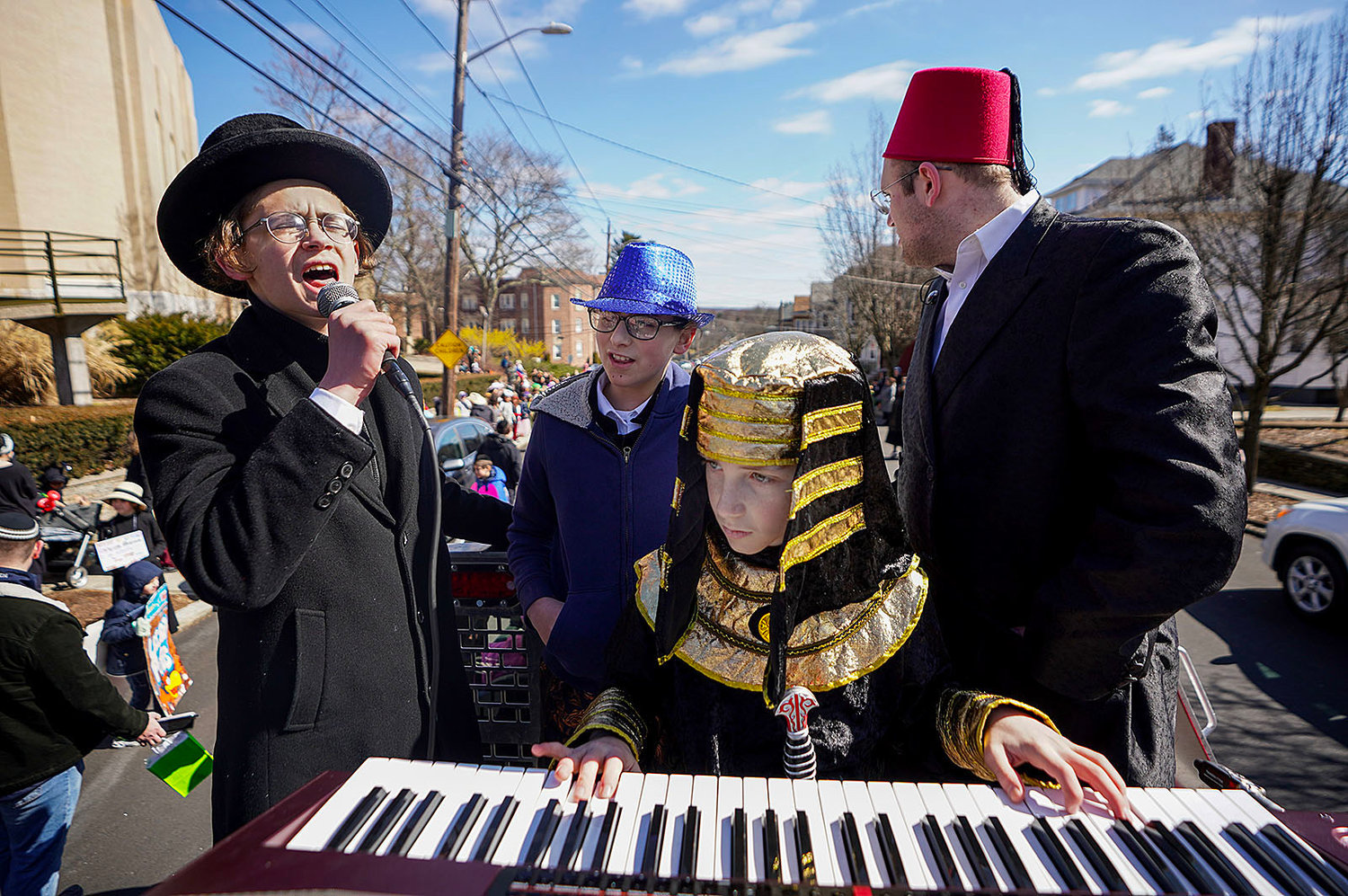 Akiva Yudkowsky, left, sings while his brother plays a keyboard on the back of a truck as the parade makes a turn onto Sessions Street.