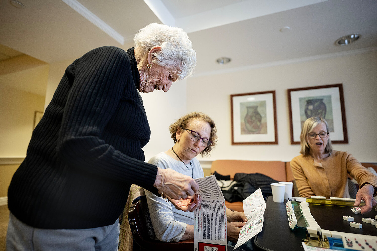 Florence Katz, standing, looks over a mahjong card with her daughter, Judy Fox, of Cranston.  On the right is Katz’s daughter-in-law, Patty Katz, of Cranston.