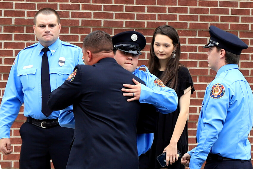 Firefighters embrace outside the church before the May 31 funeral for fallen Irmo firefighter James Michael Muller.