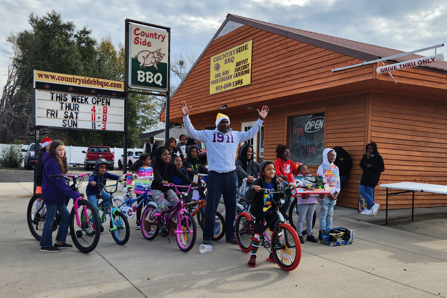 Stanley Myers stands with kids receiving free bikes at the Dec. 17 Bike Bonanza at his restaurant, Countryside BBQ.
