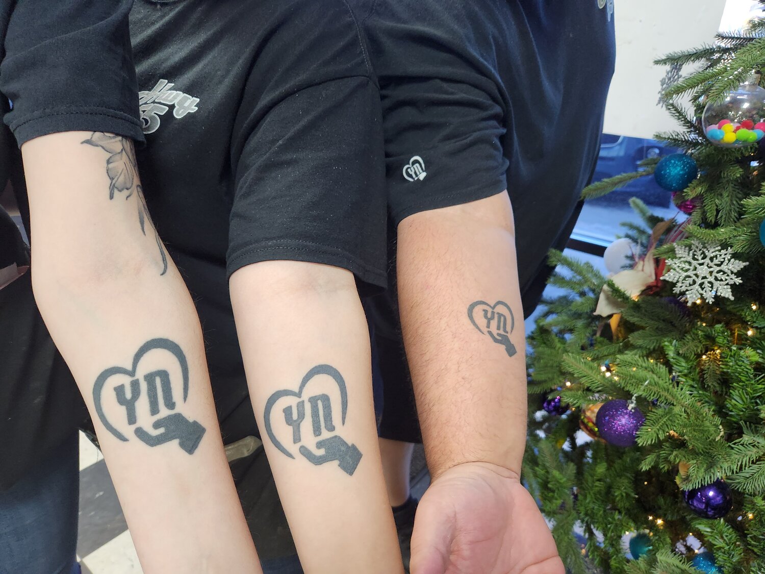 Members of the team at Hwy. 55 Burgers, Shakes and Fries in Red Bank show off “Love Your Neighbor” tattoos.