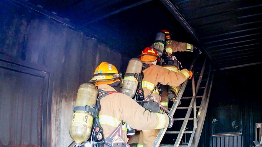 Ashley Kutac and Rachel Feld, interns with USAG Fort Sill under the Army Fellows Program, go into a fire training house with members of the Fort Sill Fire Department.