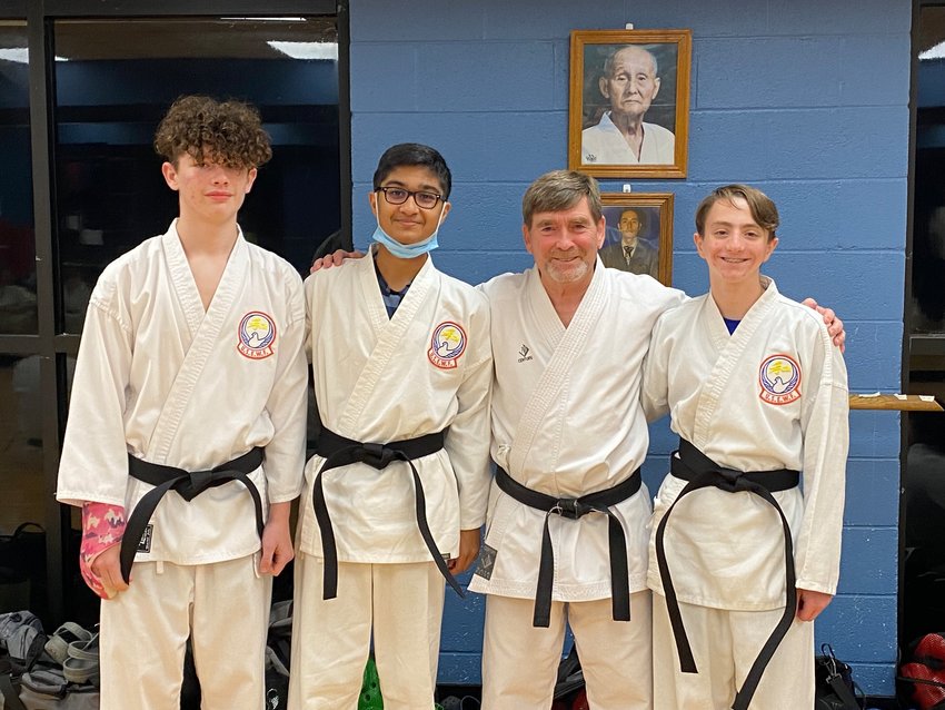 Recently promoted black belts are congratulated by their teacher. Those students are (from left) Jacob Rigsby, Jainil Patel, Sensei Monroe Carter, and Nathaniel Carter.