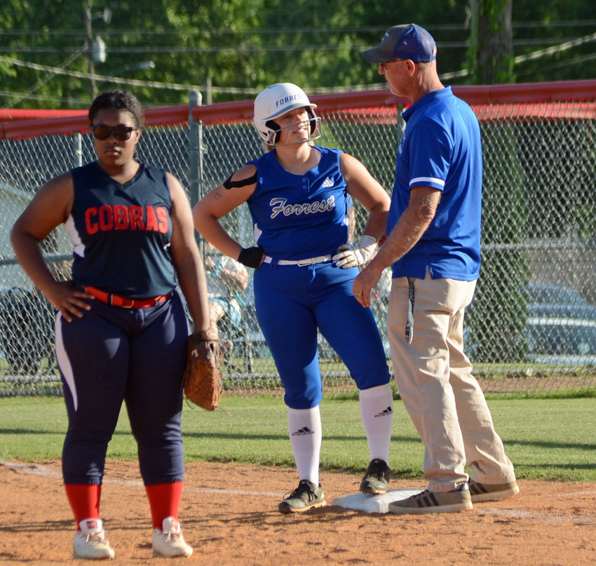 Leslie Bartoli talks with Forrest assistant coach Rickey Stinnett after reaching first base with a base on balls in the first inning.&nbsp;