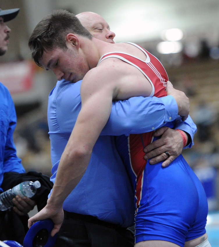 An exhausted Seth McCoy gets a hug after battling Colin Dupill in the Class A 152-pound championship match.