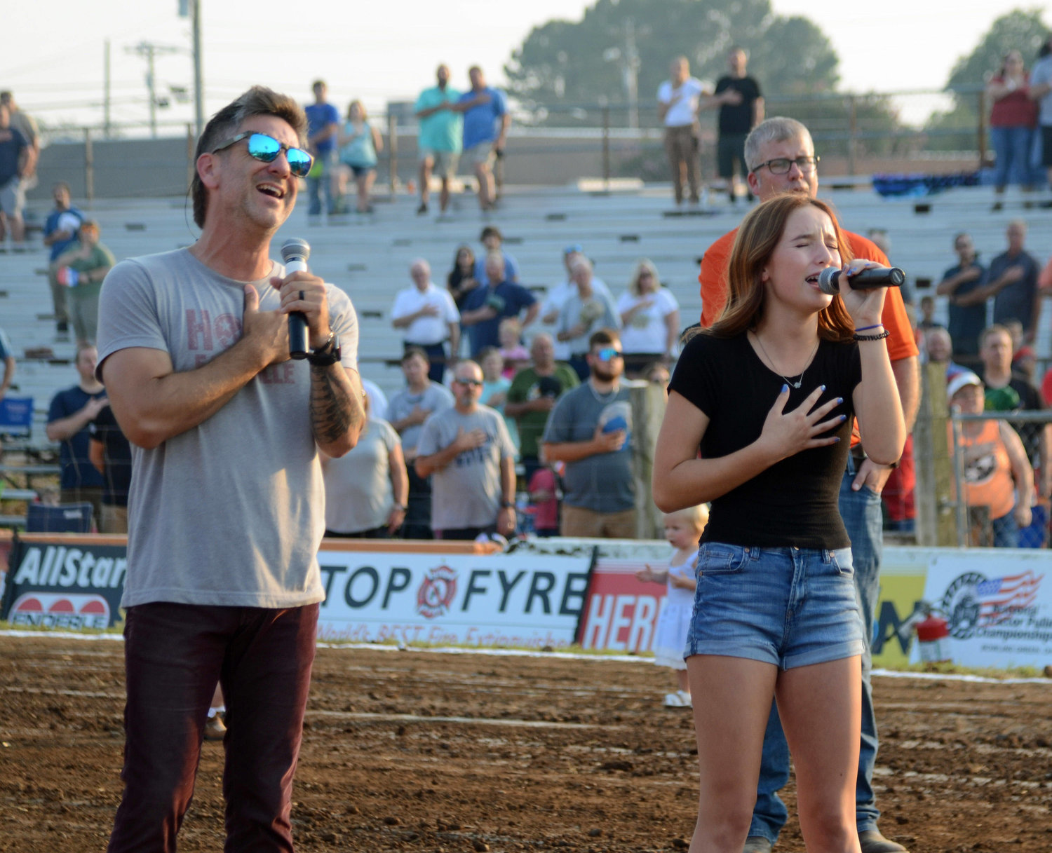 Craig Campbell and his daughter Preslee belt out the Star Spangled Banner before the start of Friday night?s opening session.