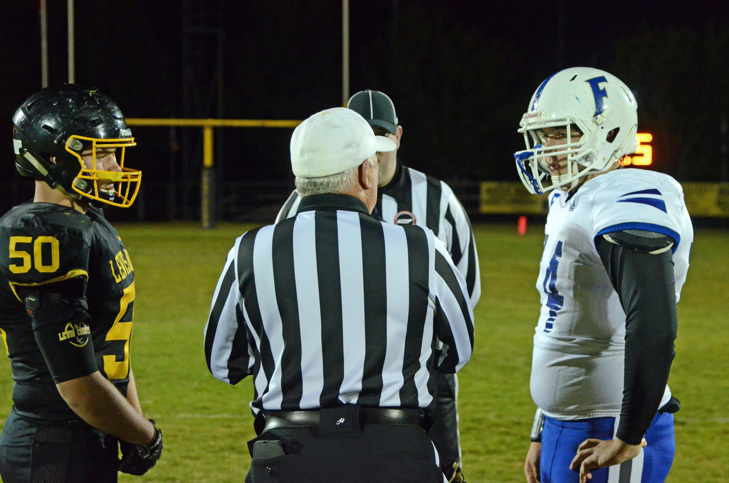 Rocket senior lineman Bridger Blue (74) and Lewis County senior lineman Ian Carroll (50) meet at midfield for the coin toss with the TSSAA referees.