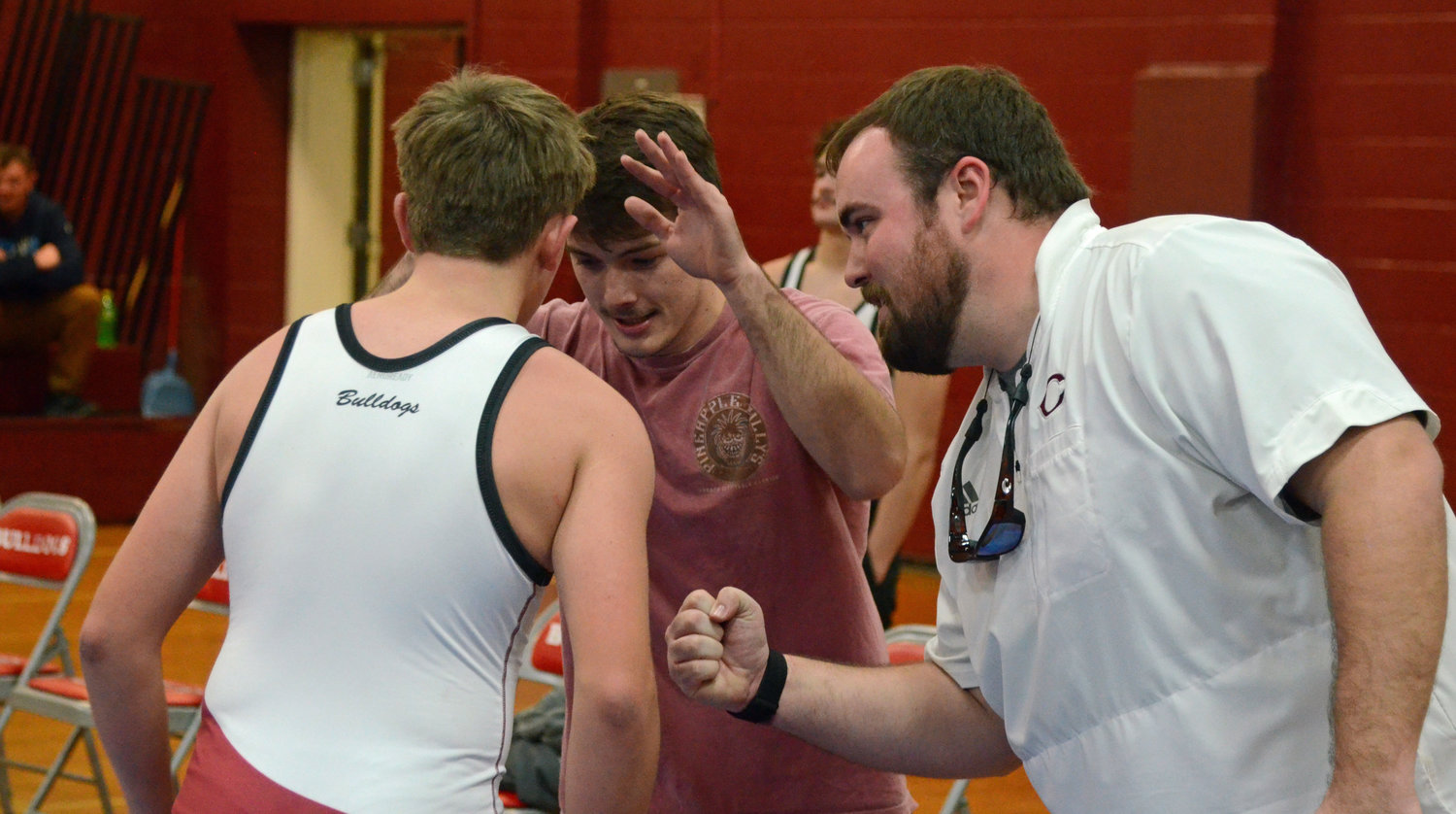 Jeff Gross (center), along with Cornersville head coach Sam Hubbell, congratulate Caden Bush after the Bulldog eighth-grader came up with a pin Tuesday night.