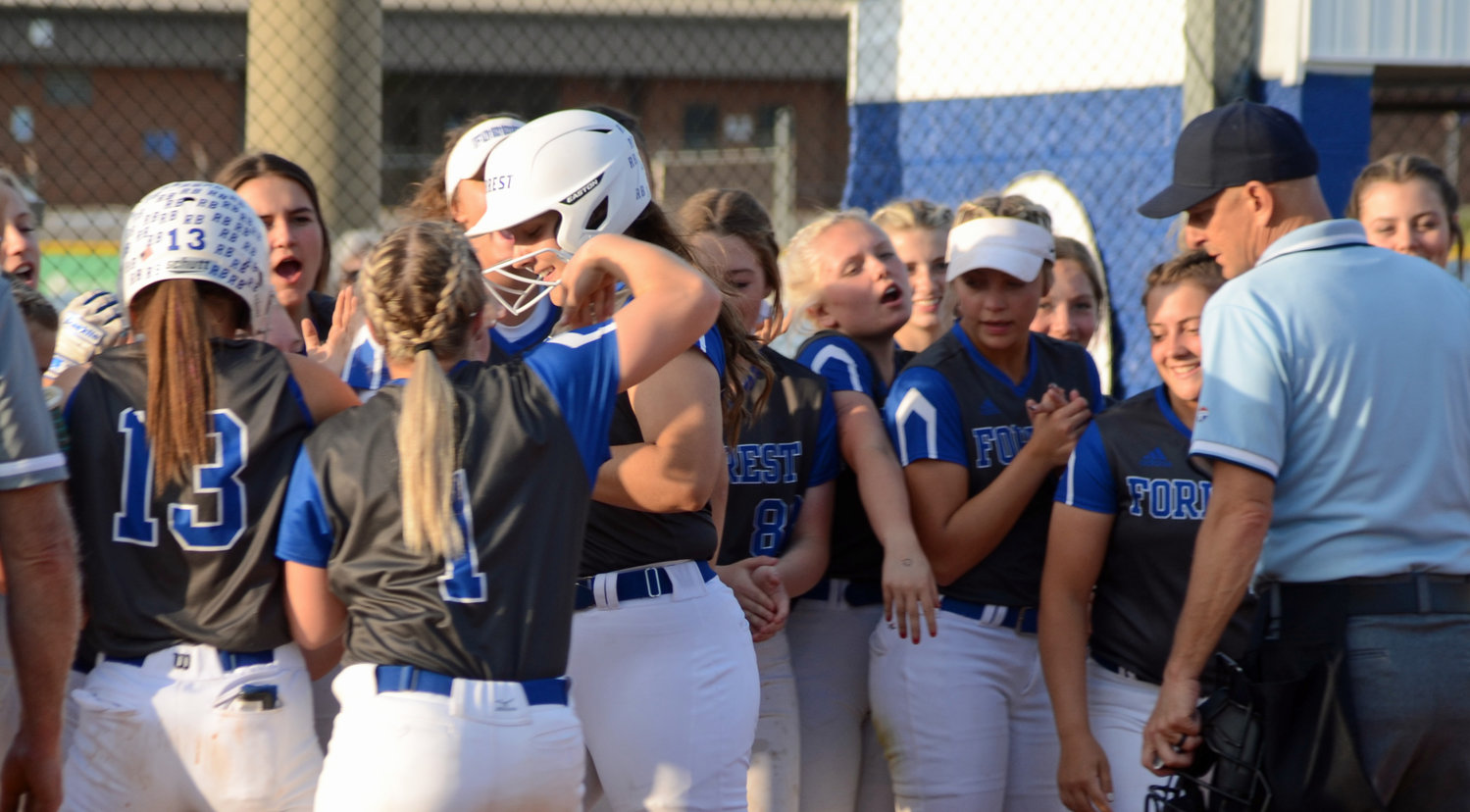 Sarah King is greeted by her teammates at home plate after bashing a two-run homerun in the bottom of the fourth inning.