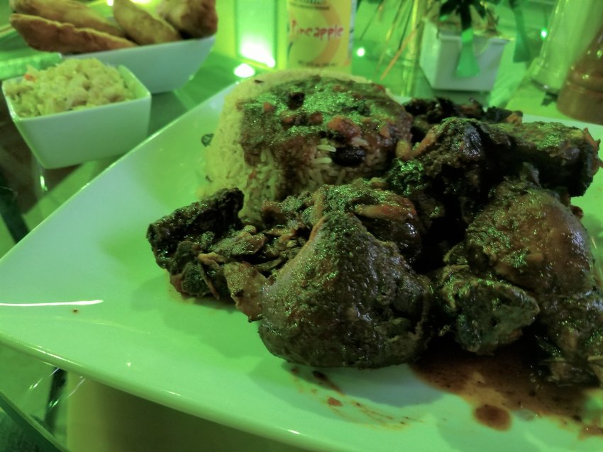 A green table lantern cannot obscure the hue of brown stew chicken at Koolrunin Yardi's in Jefferson City. [Dave Faries]