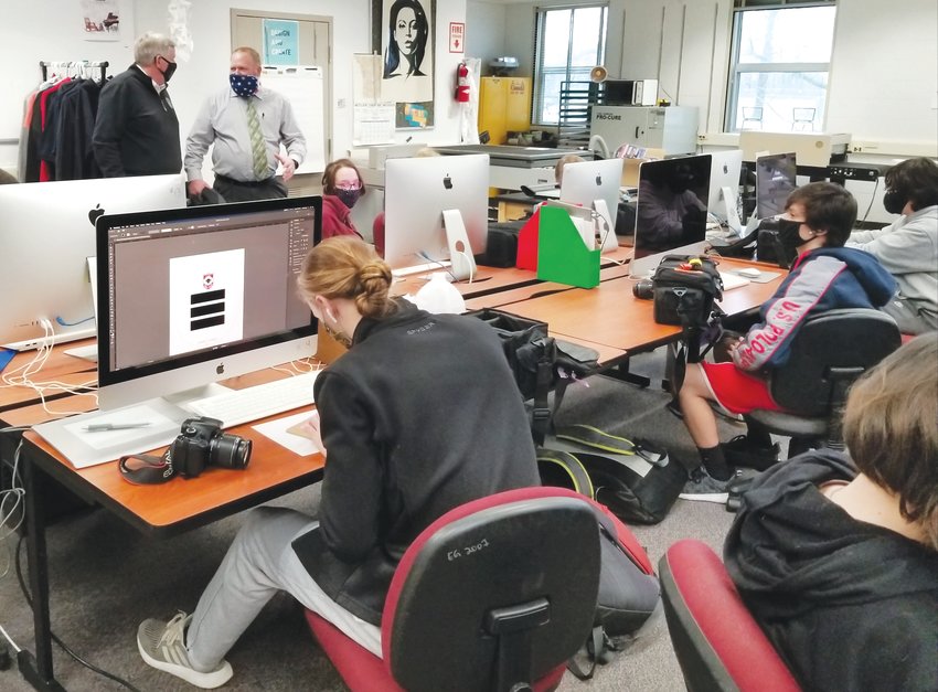 Missouri governor Mike Parson and Hart Career Center director Chris Denham discuss the range of vocational courses available at the Mexico facility while graphic arts students focus on their projects. The governor toured the Hart Center on Wednesday. [Dave Faries]