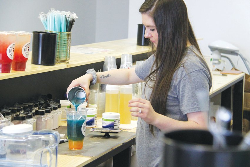 Chandlar Vlk, co-owner of The Nutrition Spot, pours a colorful tea at the recently opened space in Mexico.