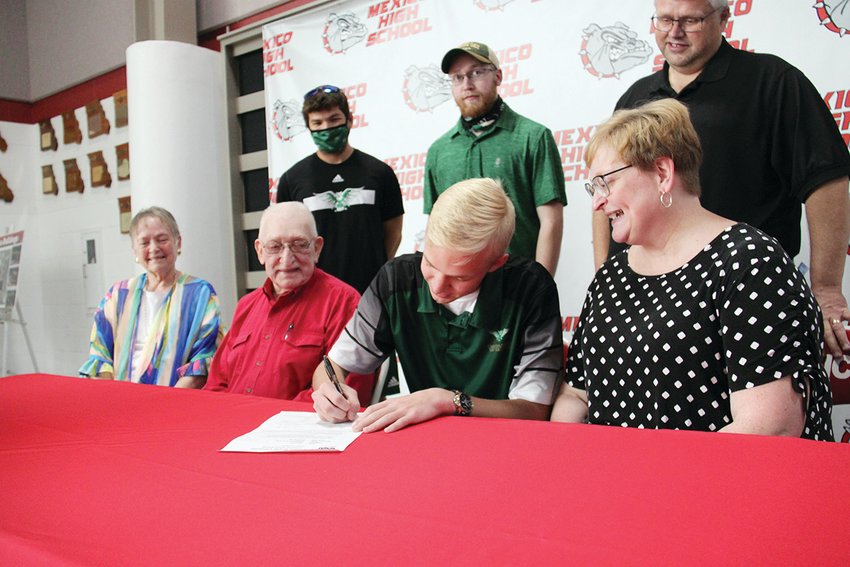 Noah Harlan signs a letter of intent to join the William Woods University tennis squad. Seated with him at Thursday&rsquo;s ceremony are his grandparents, Judy and Dale Hunt, along with his mother Lori. Standing are Harlan&rsquo;s brother Caleb and his father Aaron.