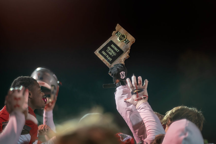 There's no place like home (to win a district title). Mexico Bulldogs raise their newly acquired hardware skyward after defeating Blair Oaks Friday night. [Eric Mattson]