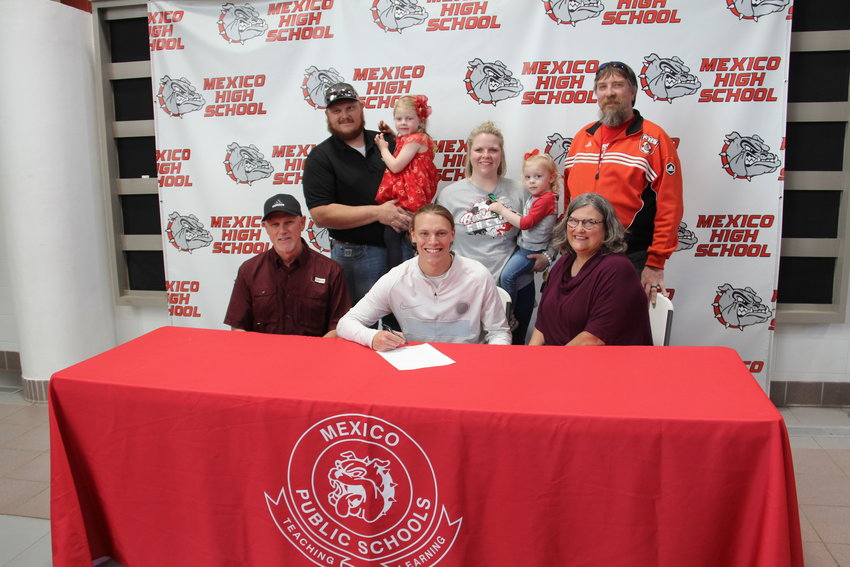 Multi-sport standout Haden Frazier signed to play soccer with the Division 1 Jefferson College Vikings in Hillsboro recently at Mexico High School. Frazier was joined by friends, family and his teammates for the event. Above, Frazier signs as his father, Jeff, and mother, Margaret look on. In the back row is his older brother, Caleb, his wife, Jenna and their kids, Phoebe (with Caleb) and Claira (with Jenna) and coach, Bill Gleeson.  [Nathan Lilley Photo]