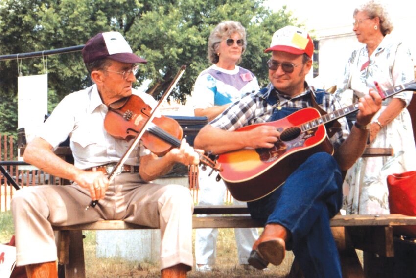 Kenny Applebee (right) accompanies Boone County old-time fiddler Pete McMahan on a bench on the grounds of the Smithsonian&rsquo;s 1991 Festival of American Folklife.