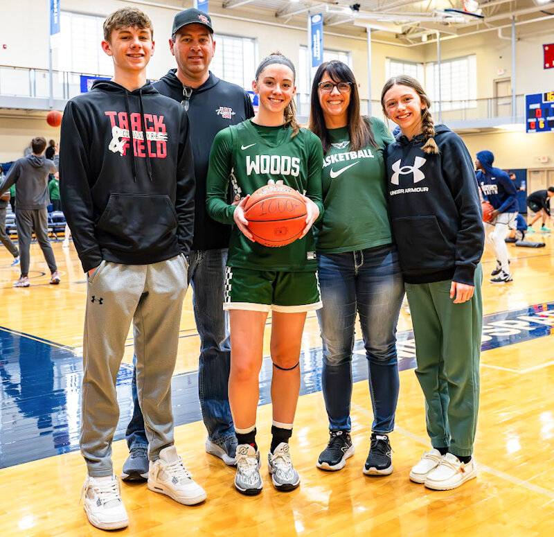 William Woods senior and Community R-6 graduate Natalie Thomas stands with her family (from left, brother, father Matt, mother Carey and sister) last Saturday while holding her commemorative 1,000-point basketball. Thomas scored her 1,000th college point almost five years after recording her 1,000th high school point as a Lady Trojan.