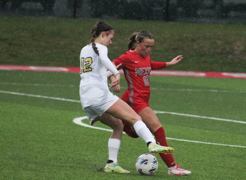 Mexico junior Kenley Jones stays close to Wright City's Paige Kirn during Monday's matchup between district opponents at Chris Hotop Field in Mexico. During nonstop rain, Kirn scored four goals to help Wright City come back and beat Mexico 4-2.
