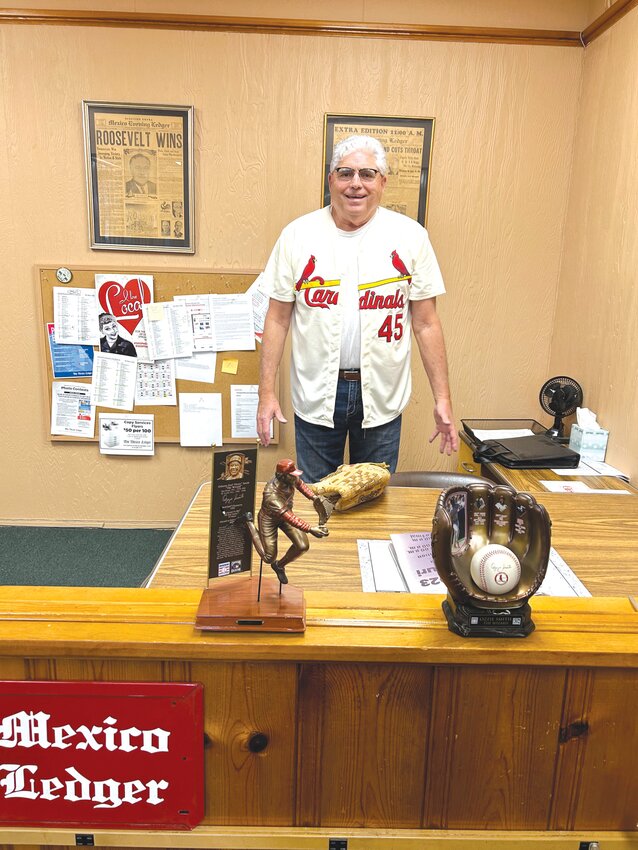 Tim Crow is warming up for a big throw Friday. He is shown here with some of the St. Louis Cardinals memorabilia he has collected over the years.