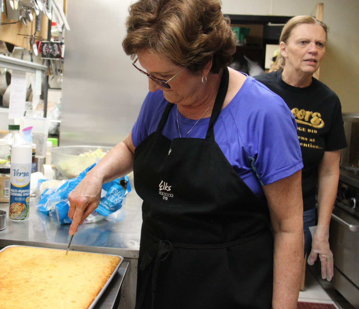 Judy Fry ignores the commotion around her in the Elks Lodge kitchen as she slices cornbread. The Elks host regular fried fish meals for members and their guests. [Dave Faries]