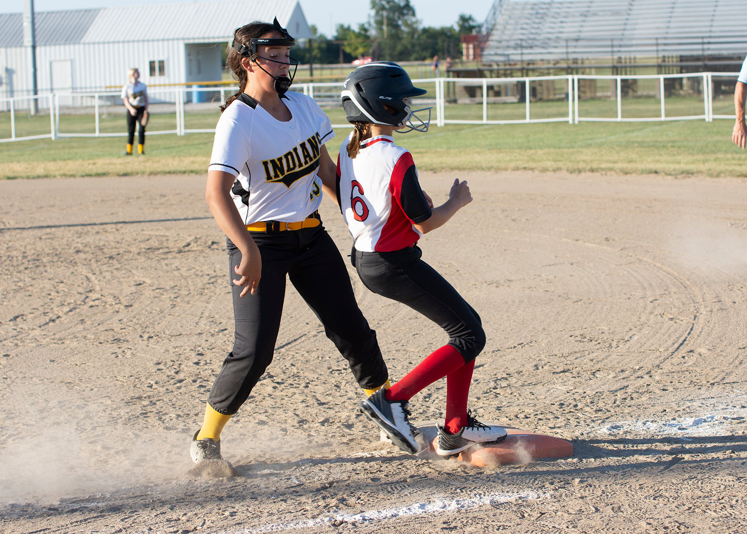 The Trojans Lydia Hoyt rushes to first base while Makayla McCurdy, first baseman for the Indians, tries to make the play during middle school softball action. [Leslie A Meyer Photography]