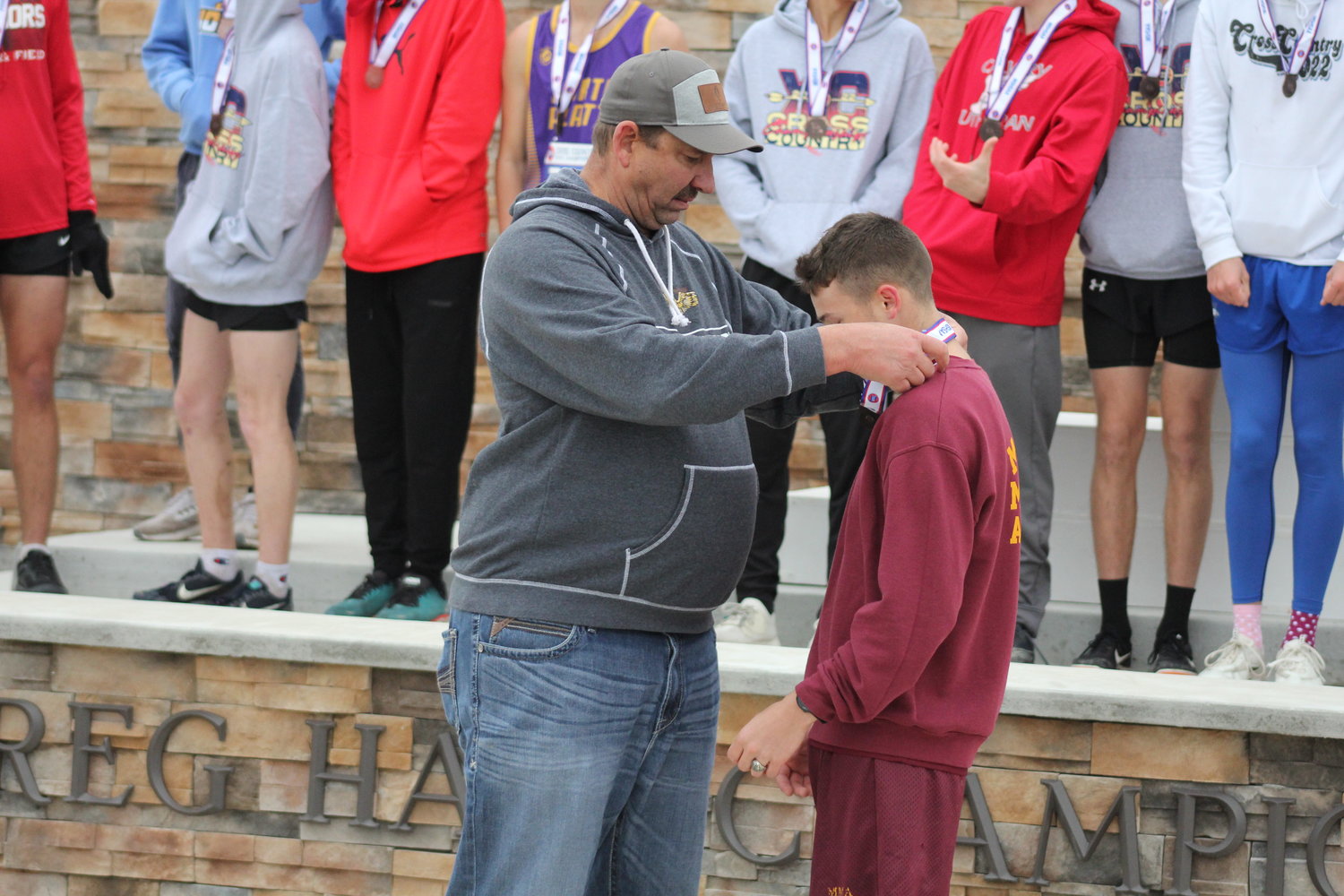 Missouri Military Academy athletic director Brian Meny medaling all-state runner Bryson Powell