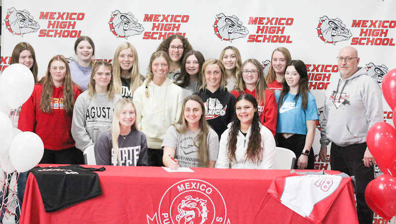 Mexico senior Kierstan Epperson is surrounded by her teammates and head coach Curt Riley on Friday during a ceremony to reveal her signing to Moberly Area Community College softball.