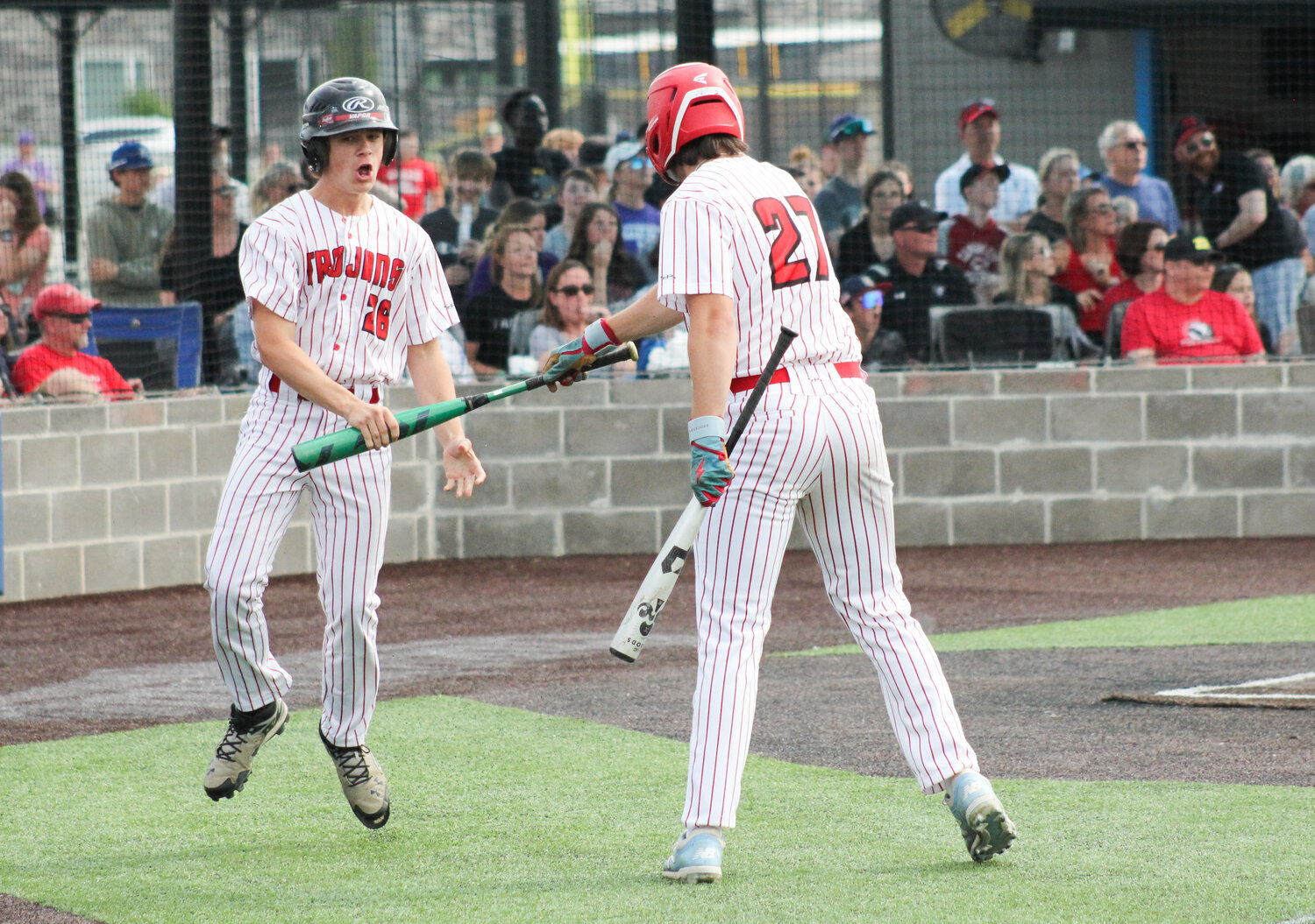 Community R-6 senior Tucker Cox takes a bat from senior Gavin Allen after scoring the first run Monday's playoff game in Parkville. Cox finished 2-for-3 with an RBI and two runs from the No. 9 spot.