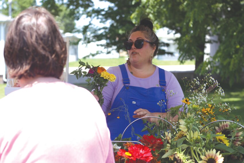 Wellsville resident Alicia Small, the owner of Small Farmstead, hands flowers to a customer at the Farmers Market on July 14 in Montgomery City.