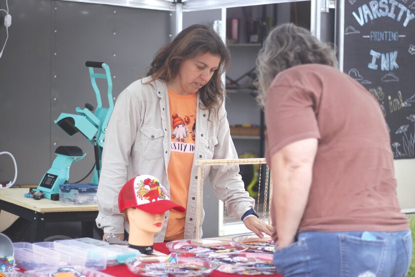 Jolene Rodgers of Varsity Ink talks with a customer at the Homestead Market on the corner of Highways K and 19 in Big Spring on the evening of September 27. It was the last Homestead Market of 2024.