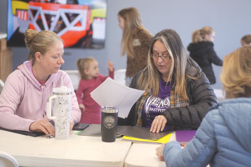 Tracie Schofield and Amy Trent, treasurer and president of the new Wellsville Community Athletic League, help with registration at the Wellsville Fire Department on March 1.