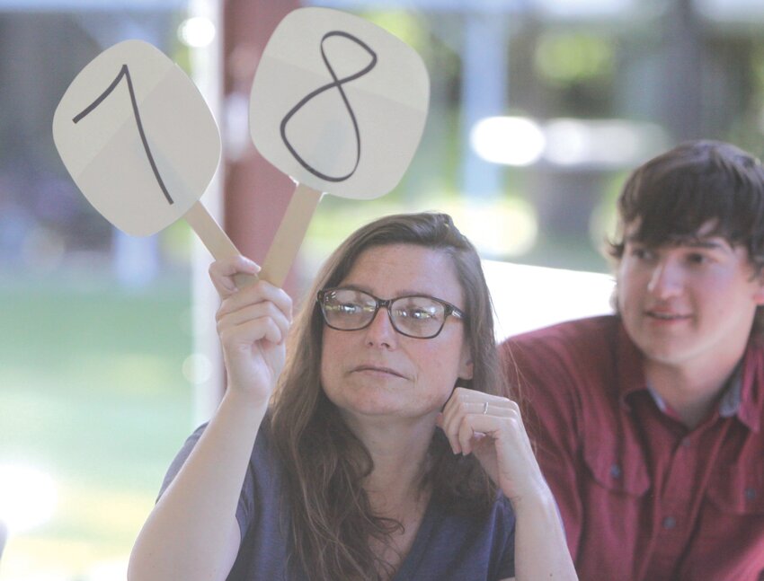 Jenny Cox holds up a pair of paddles in the 2024 Montgomery County Senior Center Paddle Auction. The event returns for its fifth year on May 30.