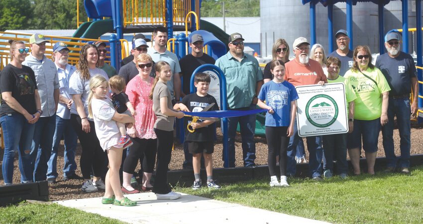 City officials and residents pose next to the new playground at Stiers Memorial Park in Rhineland on May 10. A ribbon-cutting ceremony was held to commemorate the new project. Holding the scissors is Lincoln Kolks.
