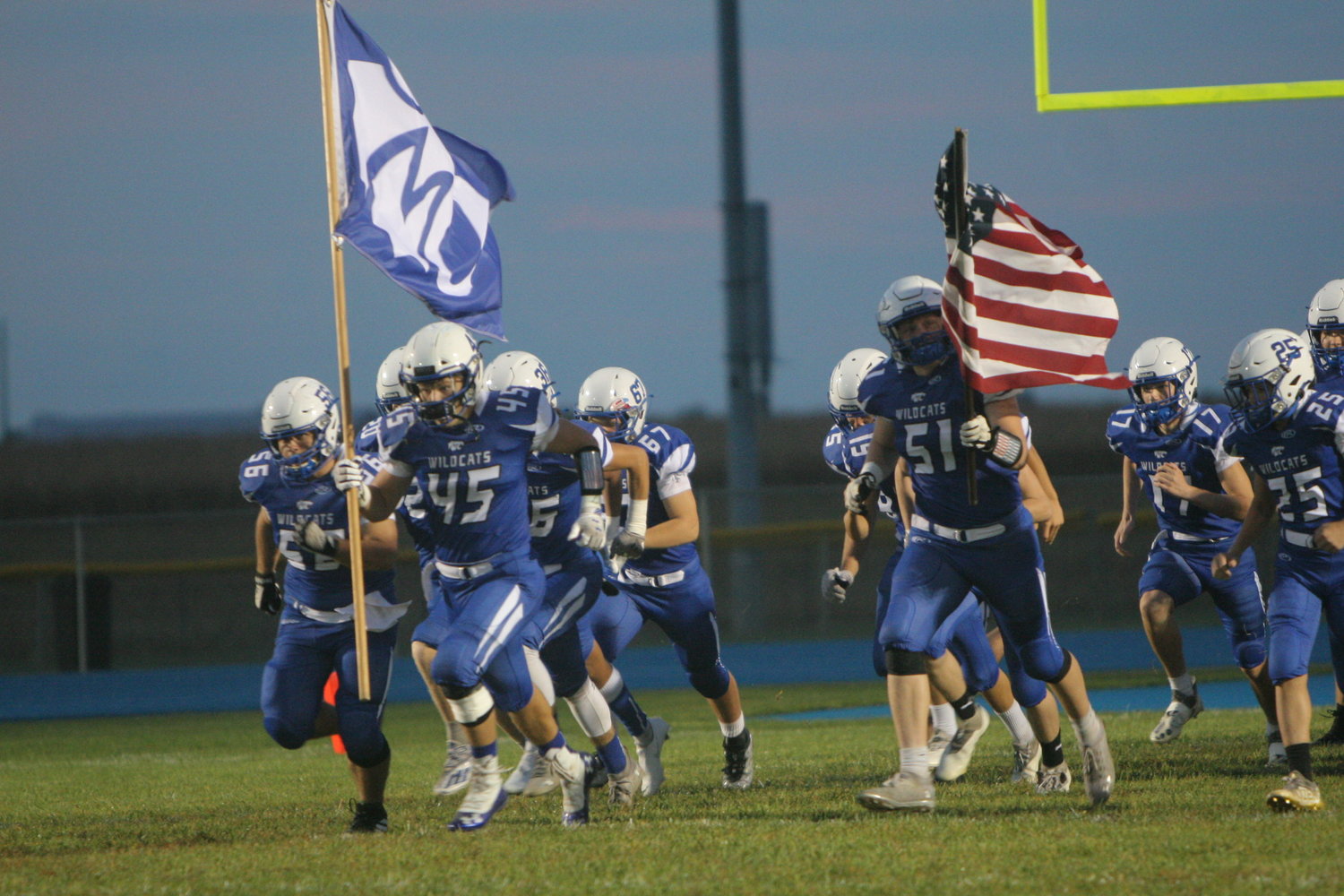 The Montgomery County football team charges to the field before its game against Greenville (Ill.) on Oct. 1. Thomas Klekamp (45) is holding the MCHS flag and Evan Abercrombie (51) is holding the American flag.