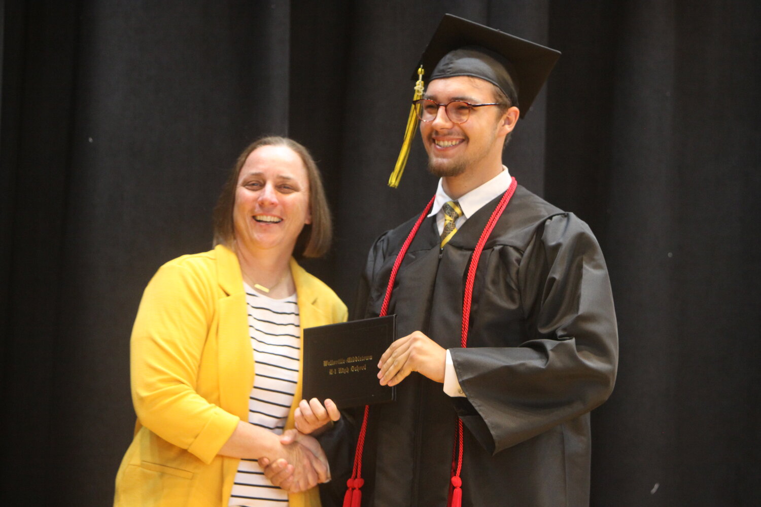 Gavin Hill, right, shakes hands with Wellsville-Middletown High School principal Jessie Cobb after receiving his diploma at the graduation ceremony on May 12. Below, Kaleb Peak speaks to the audience during the ceremony.