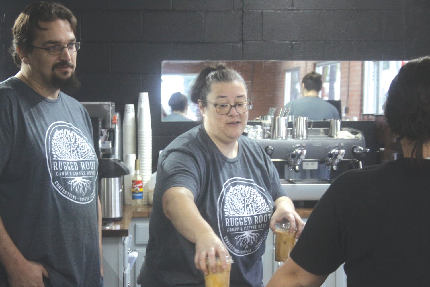 Tom and Mariah Harner hand a customer a cup of coffee on Sept. 12 at their new store, Rugged Root Candy & Coffee House in Montgomery City, which opened for business on Sept. 8.